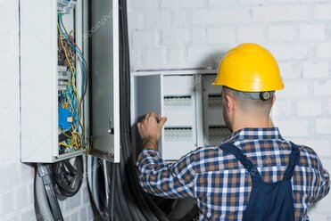 Electrician examining an electrical panel in an older home