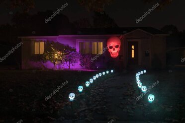 Front yard with pathway and wall-mounted outdoor lighting at night